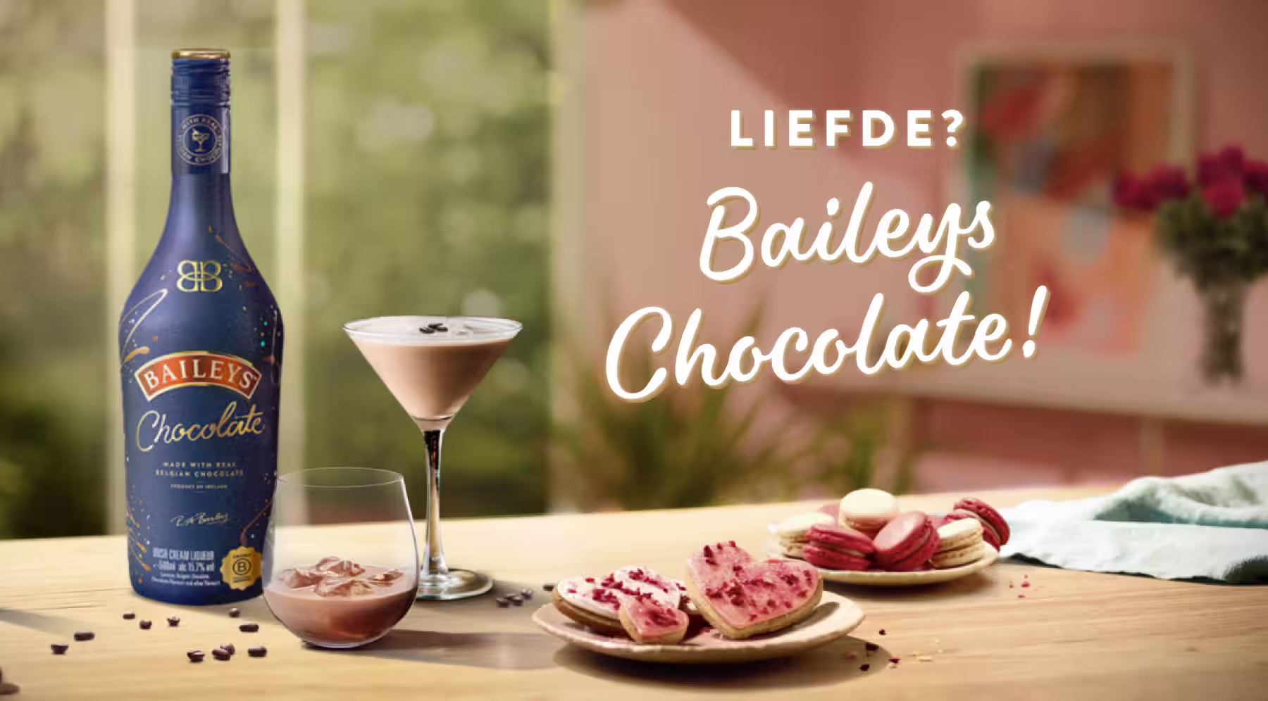 Two Baileys Original Irish Cream bottles with chocolate cocktails, cookies, and flowers on a romantic Valentine's Day-themed background.