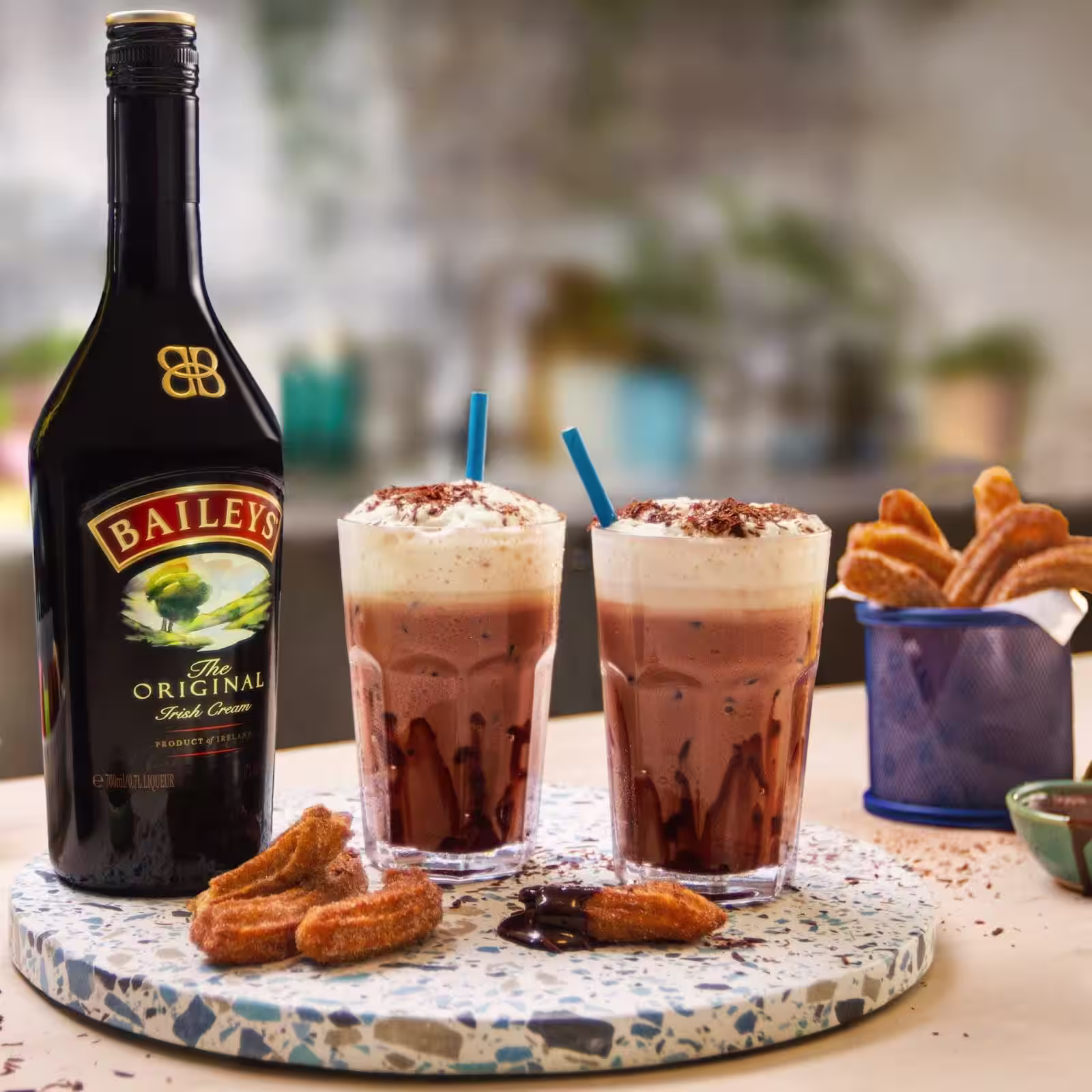 Op een toonbank staat Baileys-ijschocolade. Er staat een Baileys-fles, gesuikerde churros en chocolade-ijsjes.